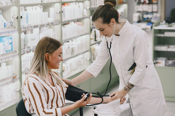 Fototapeta premium Trainee taking blood pressure of his customer in the pharmacy