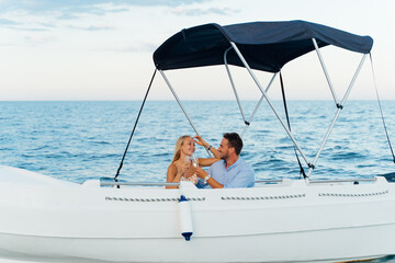 Happy young tourist couple strolling and enjoying a glass of cava on a boat.