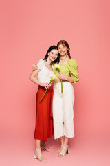 Smiling body positive women holding calla lilies on pink background