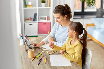 family, motherhood and leisure concept - mother spending time with her little daughter drawing with color pencils and using tablet pc computer at home