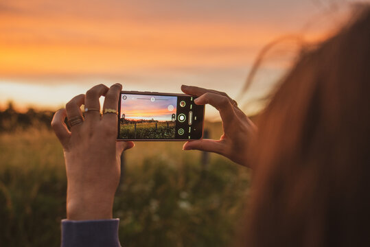 person taking pictures of a field at sunset golden hour