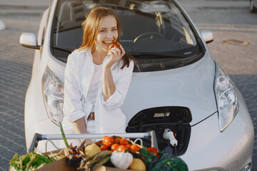 Naklejka premium Woman charging electro car at the electric gas station