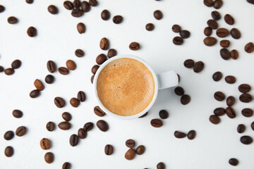 Obraz premium Cup of tasty espresso and scattered coffee beans on white table, flat lay