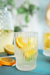 Delicious refreshing lemonade with orange slices on light blue wooden table