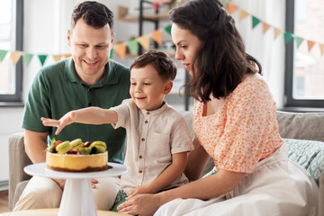 family, holidays and people concept - portrait of happy mother, father and little son with birthday cake at home party