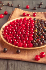 On the rustic table, ripe cherries and black currants on a dessert plate