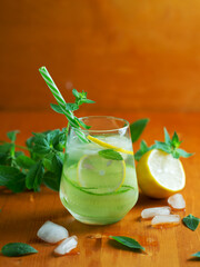 Refreshing lemonade with cucumber, lemon and mint on a wooden table