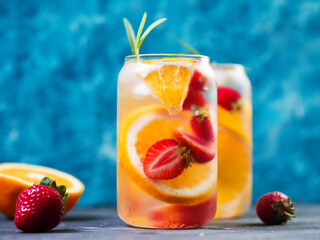 Infused detox water with orange, strawberry, lemon and rosemary. Summer refreshing lemonade, colorful bright background