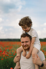 Happy father's day. Little boy and father are playing in a beautiful field of red poppies.