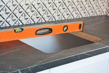Kitchen sink installation. A close-up of a kitchen worktop with a hole for sink installation and a spirit level to check the horizontal level.