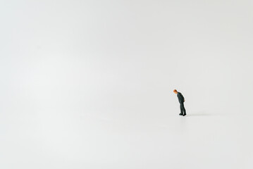 Miniature people A depressed Businessman mini figures standing thinking on white background using as Success Business partnership development and Commerce Strategy Planning concepts.
