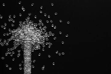 white granules of rubber and polypropylene on a black background in a chemical test tube. Plastics...