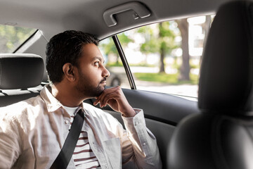 transportation, vehicle and people concept - thinking indian male passenger in taxi car
