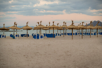Empty Sun Loungers and Straw Umbrellas on a Beach in Mallorca in the Balearic Islands