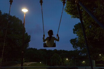 夏の夕方の公園でブランコを遊んでいる子供の様子