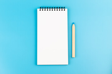 Blank paper and a colorful pencil on a blue background