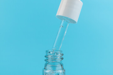face serum drop with bottle on blue background.