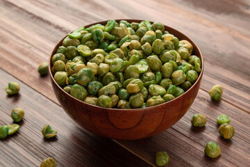 Salted green peas in wooden bowl on the table, Healthy snack, Vegetarian food.