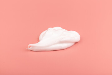 White cosmetic cream smear isolated on pink background. Skincare product creamy texture.