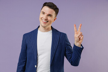 Smiling joyful young successful employee business man corporate lawyer 20s wear formal blue suit white t-shirt work in office showing victory sign isolated on pastel purple background studio portrait
