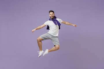 Fototapeta na wymiar Full size body length fun young brunet man 20 wear white t-shirt purple shirt jump do clapping gesture with legs isolated on pastel violet background studio portrait. People emotion lifestyle concept