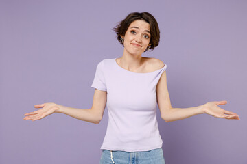 Young confused uncertain doubtful displeased sad woman 20s with bob haircut wear white t-shirt spreading hands asking isolated on pastel purple background studio portrait. People lifestyle concept