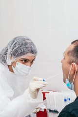 A medical worker taking mouth swab from middle-aged man to test for possible coronavirus infection in clinic.Medical and coronavirus concept.