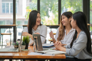 Fototapeta premium Businesswoman discuss their work during a coffee break at the office with financial reports, coffee cups, and plants decor