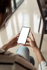 Close-up of a woman hand holding a smartphone blank white screen work concept. Mock up.