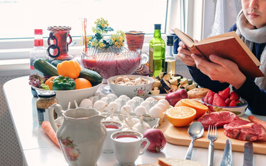 Man reading a book on dining table with various material cooking ingredients for the celebration in the festival