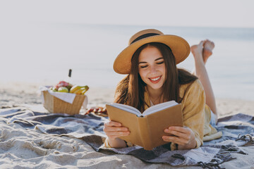 Full size young happy traveler tourist woman 20s in straw hat shirt summer clothes read book lying...