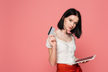 Woman with vitiligo holding digital tablet and credit card isolated on pink