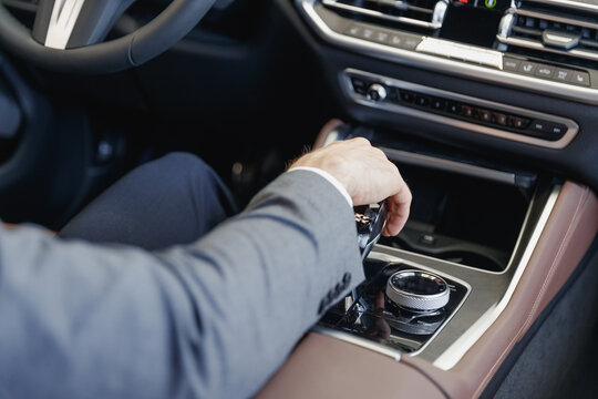 Close up cropped up photo shot of arms male hand in classic grey suit driving car hold wheel change gears in new modern automobile vehicle black luxury stylish salon Sale technology lifestyle concept