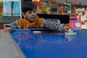 Little brunette boy playing table hockey in a playroom. horizontal and blur background