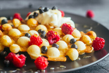Delicious hong kong waffles. Waffles with raspberries, blueberries, sour cream and honey. Waffles on the table 