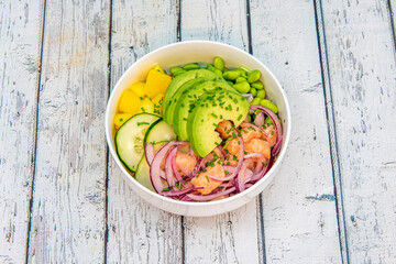 Poke bowl with salmon marinated with lime as if it were a ceviche with sliced avocado, edamame beans, purple onion, raw cucumber and chopped mango.