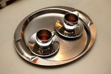 a pair of silver cups on a silver tray