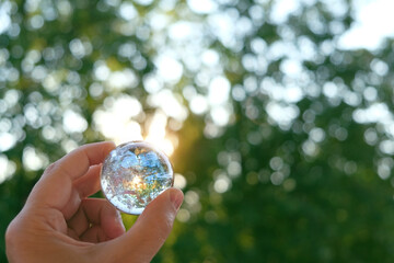 Clear quartz crystal ball in hand,  natural green background. Esoteric spiritual practice....