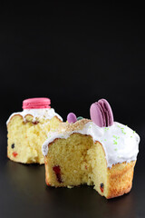 Easter cake and its piece decorated with macaroons isolated on dark background
