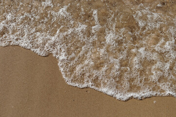 Tidal waves with ripples and foam on sea coast