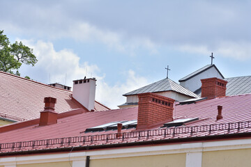 The roof of the church over the roofs of buildings. Summer. Day.