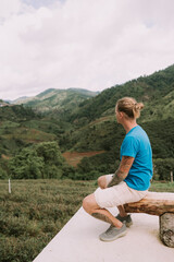Man tourist sitting on a bench at Tea plantation in mountain, Doi Mae Salong