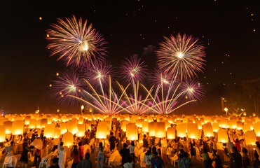 Thai people release sky floating lanterns or lamp to worship Buddha relics at night with fireworks....