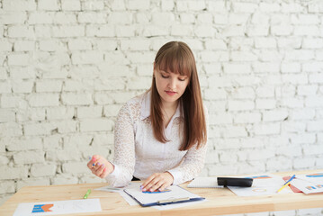 Beautiful young woman in elegant casual wear looking at chart while standing in office