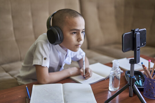 Young pupil listening to an online class with headphones at home - concept of remote classes