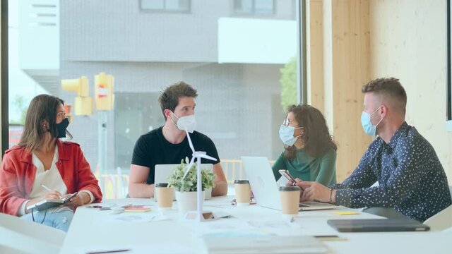 Video of successful concentrated business team wearing a hygienic facial mask while working together in coworking place.