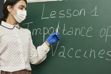 Teacher wearing a facemask and teaching about the importance of vaccines to the class