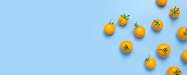 Ripe fresh yellow orange tomatoes with green tails on blue background flat lay top view. Cherry tomatoes. Vegetables, healthy vegan organic food, harvest concept, tomatoes pattern layout, cooking