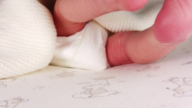 Close up shot of newborn baby in diaper lying on back and jerking her small legs