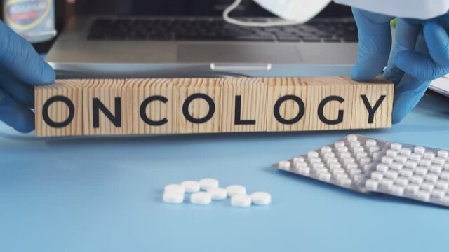Wooden cubes with inscription oncology are placed by doctor on table. Appearing cubes with the word oncology complement the medical table full of medicines